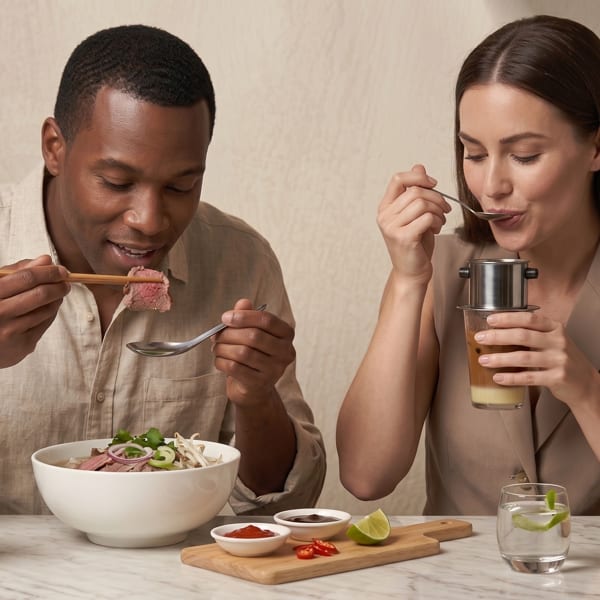 Two people enjoying Vietnamese pho and iced coffee drinks from Phi Coffee & Tea.